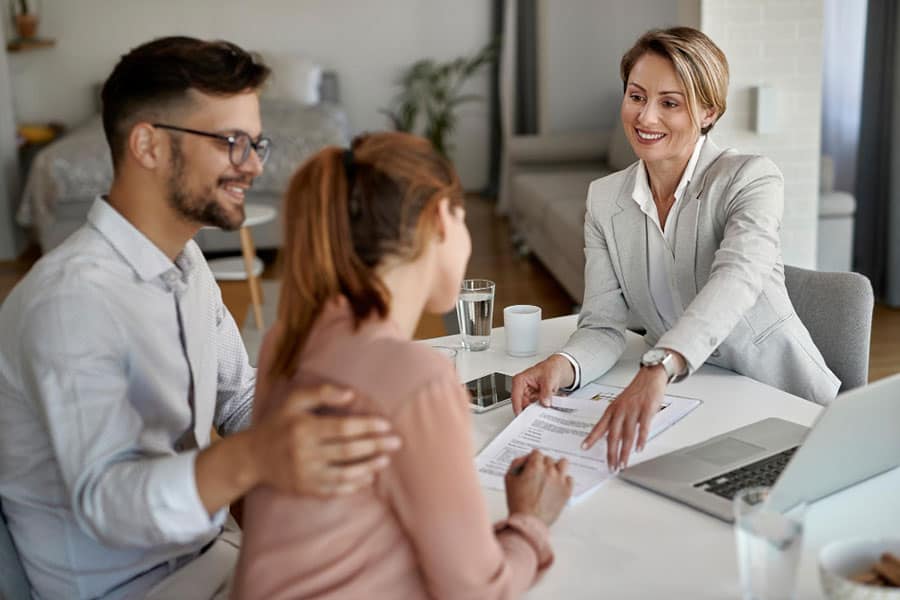 Happy Real Estate Agent Having Meeting With Young Couple Pointing Place Signature Their Contract What Is A Jumbo Mortgage In Texas